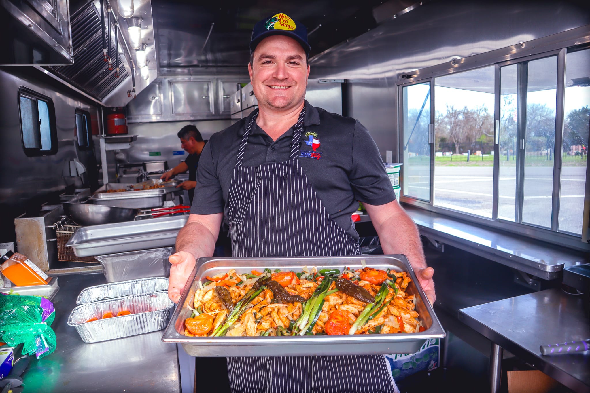 Texas Holy Chef holding tray of grilled food.
