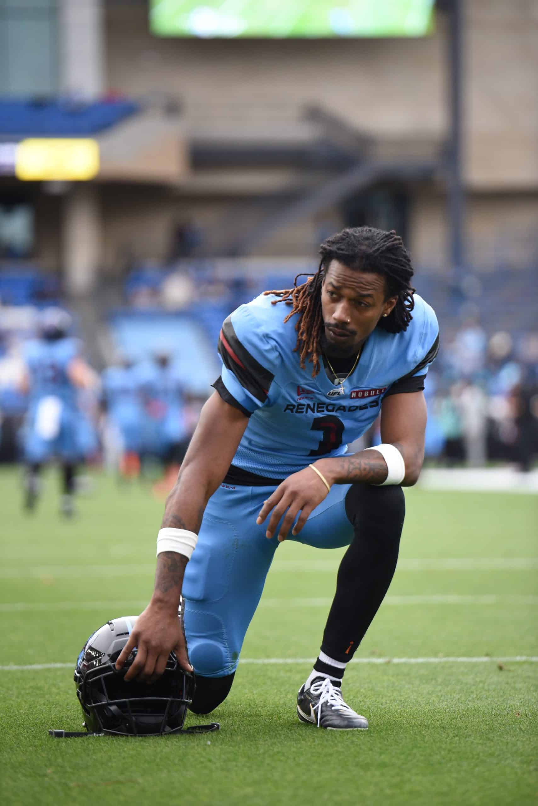 Tyler Vaughns UFL Football player kneeling on field.
