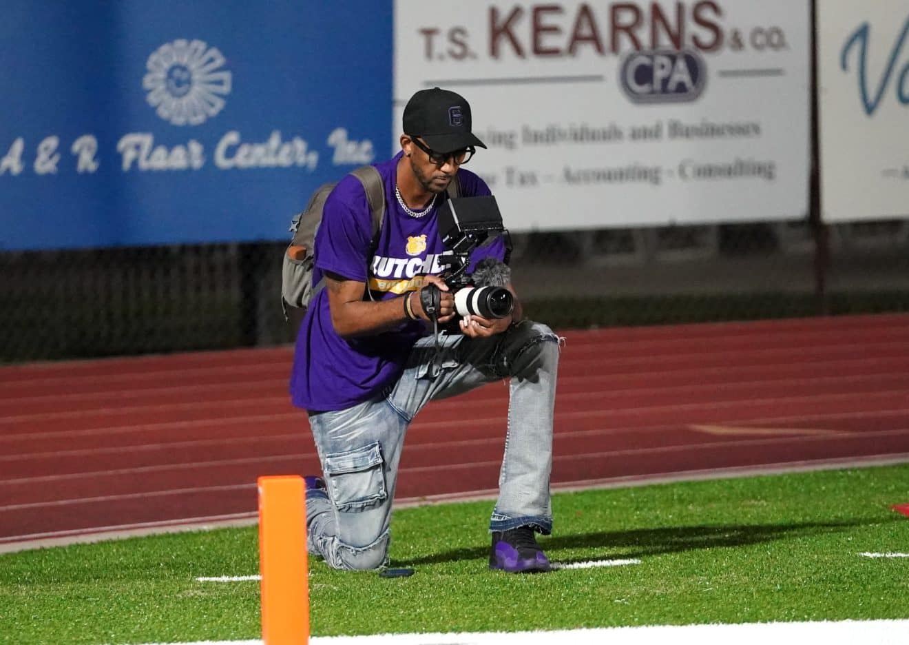 Photographer kneeling on football field